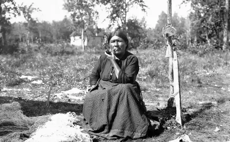 A First Nations woman smoking a pipe, taken close to what is currently Manitoba, CA.  c1900-1910
